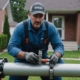 Professional plumber relining a pipe with specialized equipment in front of a suburban home.